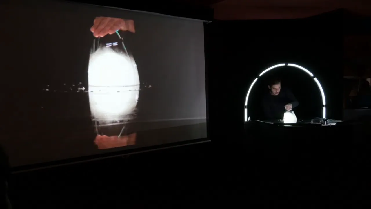 Sur scène, une bulle lumineuse filmée en gros plan et projetée sur un grand écran